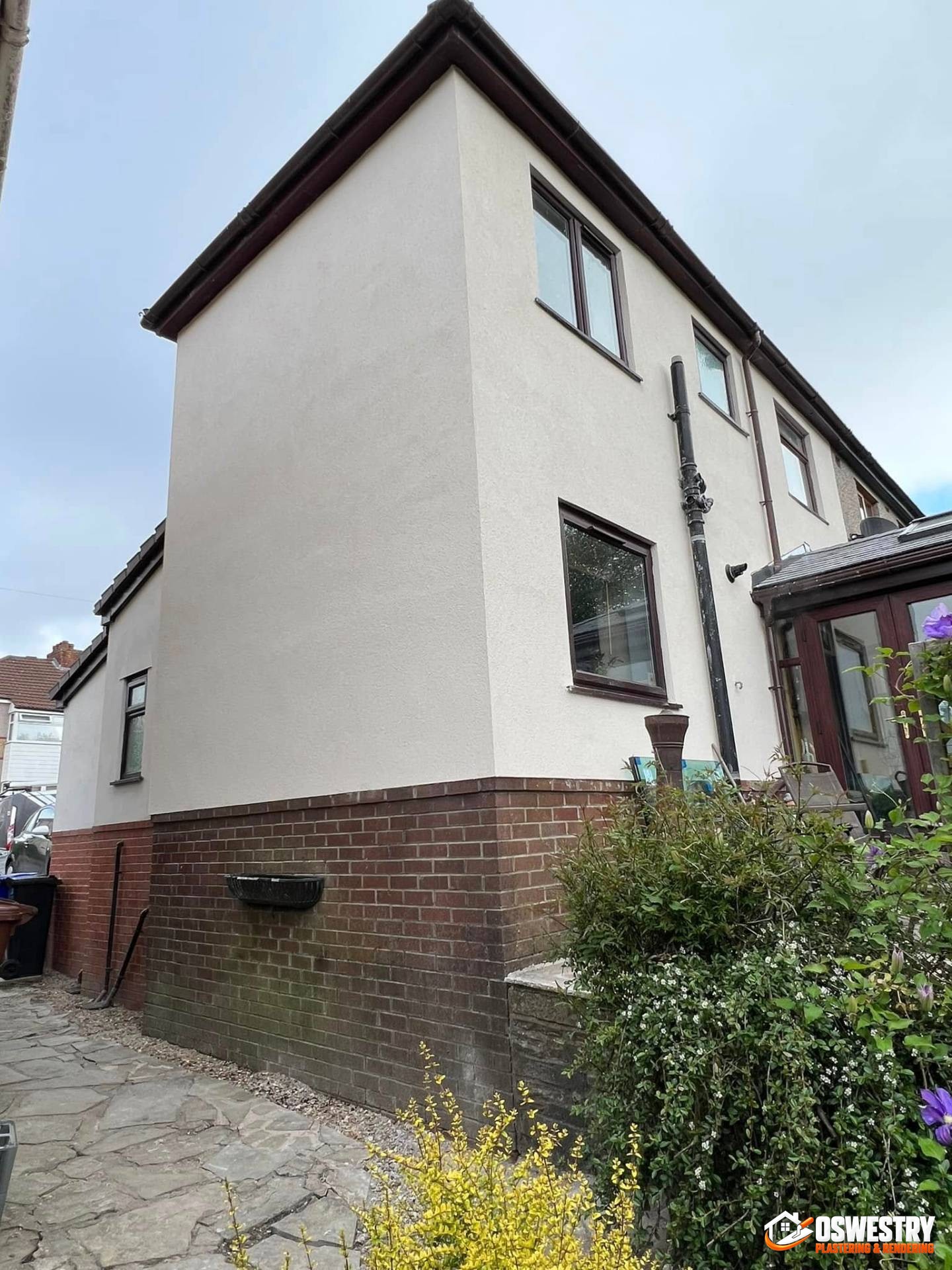 Oswestry Plastering & Rendering tradesman applying smooth white render to an exterior wall